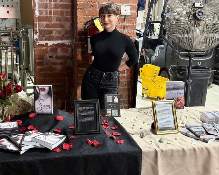 Author Chloe Ruffennach with her book table display of the sci-fi novel Siren and the domestic suspense novel Wisteria Drive.